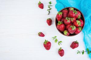 Fresh strawberry in bowl on wooden background photo