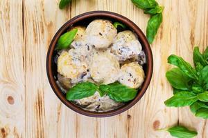 Meatballs with cream and mushrooms on wooden background photo