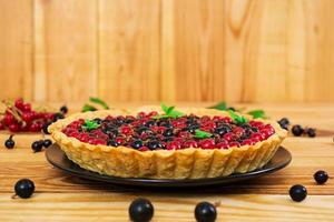 Delicious tart with custard and currant on wooden background photo