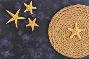 Rope and starfish on dark background. Top view photo