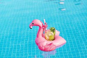 mojito de cóctel fresco en un juguete inflable de flamenco rosa en la piscina. concepto de vacaciones. foto