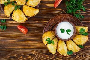 Delicious baked empanadas on wooden background photo