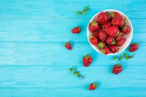 Fresh strawberry in bowl on wooden background photo