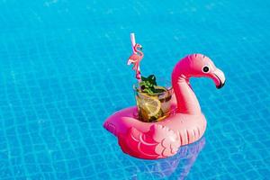 mojito de cóctel fresco en un juguete inflable de flamenco rosa en la piscina. concepto de vacaciones. foto