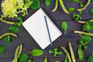 Fresh asparagus and green herbs on dark background. Top view photo