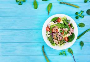 Salad with tuna, tomatoes, quail eggs, asparagus and onions on wooden background photo