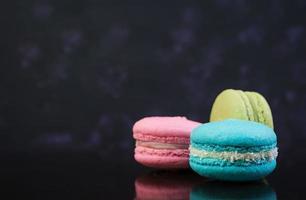 Delicious colorful macaron cakes on dark background photo