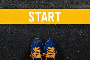 word Start on yellow line with blue sneaker or sport shoes on asphalt road background. photo