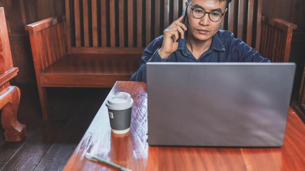 Young man working from home using smart phone and notebook computer. photo