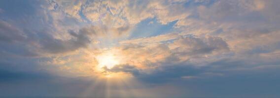 The sun in the blue sky with clouds. Rays shine through the clouds. Panoramic shot. photo