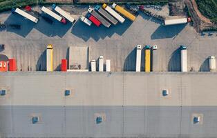 Trucks are loaded and unloaded in the cargo terminal - aerial top vu drone shot.