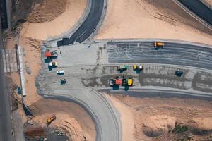 Road Construction of wide asphalt road with help of road transport equipment, top view