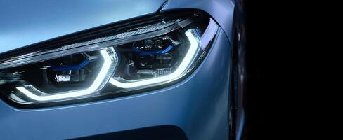 front headlight with xenon light of blue modern car on black color background and copy