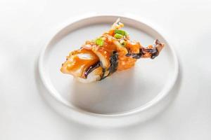 One piece of squid sushi on a white plate photo