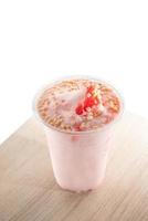 Strawberry smoothie with toppings in a plastic cup. photo