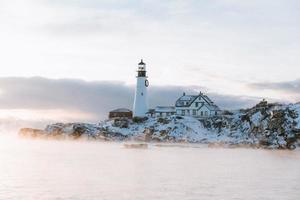 Lighthouse on snowy rocks photo