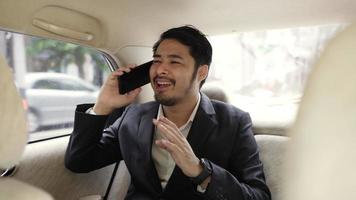 Slow-motion of a handsome businessman using his mobile phone while traveling in a modern car with a driver in the center of the city. businessman talking on video chat in a business car.