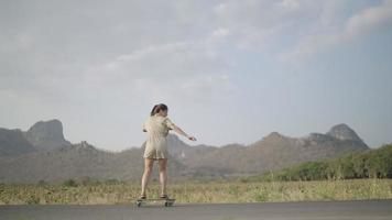 Asian women surf skateboarding on the streets outside the country road with mountain views in the evening. lifestyle concept.