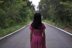 asian woman standing in the middle of the road on a green forest background photo