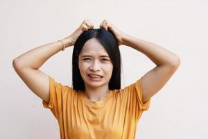 Asian woman scratching her head with her hand due to itching from dandruff photo