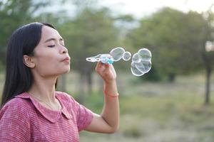 mujer asiática soplando pompas de jabón cada fondo de hierba verde foto