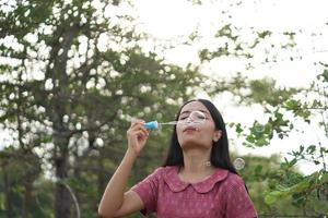 Asian woman blowing soap bubbles every green grass background photo