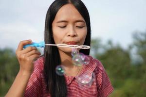 Asian woman blowing soap bubbles every green grass background photo