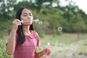 Asian woman blowing soap bubbles every green grass background photo