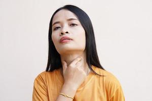 Asian woman put her hand on her neck due to irritation and sore throat photo