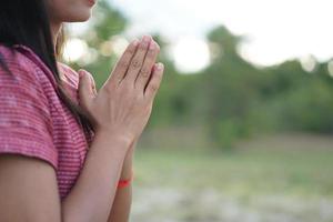 la mano de una mujer asiática pidiendo bendiciones de dios fondo de pradera verde foto