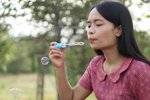 Asian woman blowing soap bubbles every green grass background photo