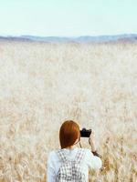 mujer viajera tomando fotos del campo de trigo en el fondo natural de la mañana.