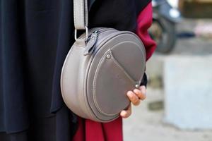 A woman's hand holds a gray sling bag photo