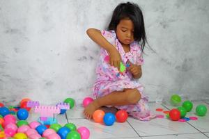 Portrait of little girl playing colorful balls in the house photo