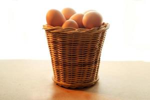 A basket of chicken eggs on a wooden table photo