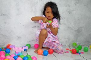 Portrait of little girl playing colorful balls in the house photo