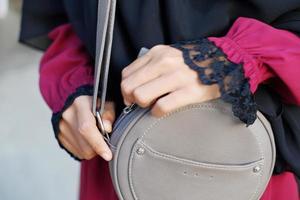 A woman's hand holds a gray sling bag photo