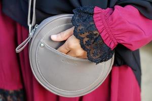 A woman's hand holds a gray sling bag photo