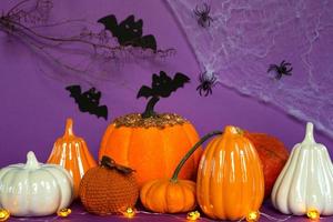 Halloween backgrounds of white, orange and gold pumpkins, spiders and black bats on a purple background with cobwebs and terrible scenery. Horror and a scary holiday with copy space photo