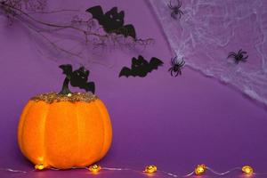 Halloween backgrounds of white, orange and gold pumpkins, spiders and black bats on a purple background with cobwebs and terrible scenery. Horror and a scary holiday with copy space photo