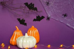 Halloween backgrounds of white, orange and gold pumpkins, spiders and black bats on a purple background with cobwebs and terrible scenery. Horror and a scary holiday with copy space