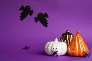 Halloween backgrounds of white, orange and gold pumpkins, spiders and black ghost on a purple background with cobwebs and terrible scenery. Horror and a scary holiday with copy space photo