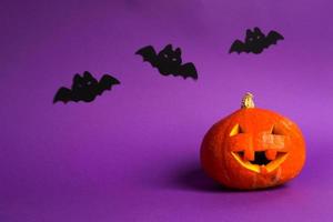 Halloween backgrounds of Jack lantern natural pumpkin, spiders and black bats on a purple background with terrible scenery. Horror and a scary holiday with copy space photo