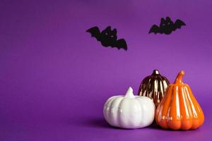 Halloween backgrounds of white, orange and gold pumpkins, spiders and black bats on a purple background with cobwebs and terrible scenery. Horror and a scary holiday with copy space photo