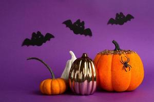 Halloween backgrounds of white, orange and gold pumpkins, spiders and black bats on a purple background with cobwebs and terrible scenery. Horror and a scary holiday with copy space photo