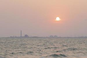 red sun in the sky and evening clouds are over Tangyard. In the petrochemical industry .The front is sea and white waves. photo