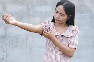 Woman scratching arm from itching on gray background photo