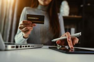 concepto de pagos de compras en línea. mano de mujer de negocios usando teléfonos inteligentes, pagos de tabletas y tarjeta de crédito foto