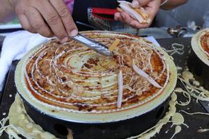 la mano está poniendo salchichas en crespones crujientes, bangkok, tailandia. el comprador puede elegir el ingrediente en crespón. foto