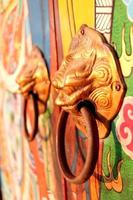 Brass door knobs are on bright colorful door and shape tiger head, the door knobs are design chinese style in shrine, Thailand. photo